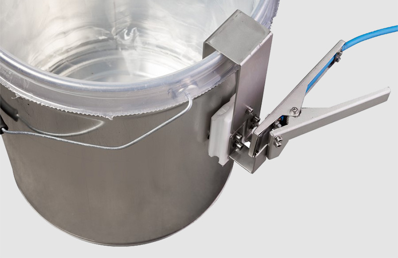 A grounding clamp conducts static electricity from a dispense bucket with a plastic inlay.